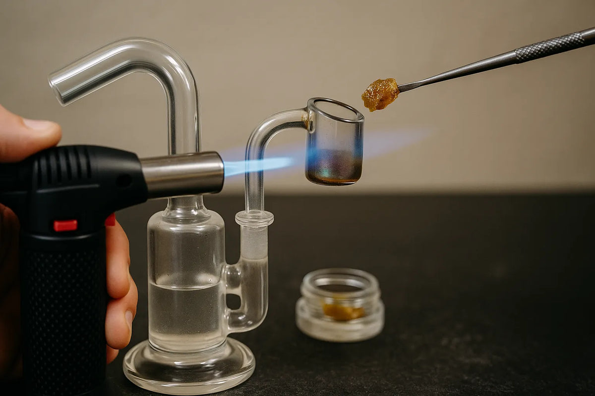 En person bruger et dab rig til at inhalere cannabis-koncentrat, close-up i en afslappet hjemmestemning.